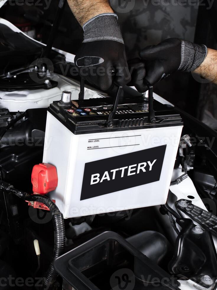 Car battery replacement , Automotive repair concept. Hands installing a car battery in a vehicle engine bay. Indoor shot of garage. photo