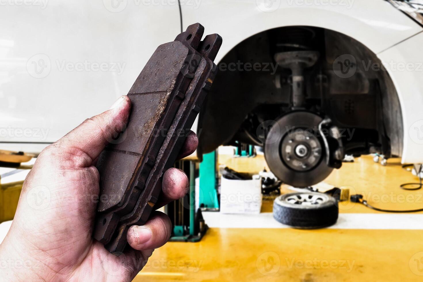 Close up of used brake pads in a automotive workshop , Car brake pads inspection , Car maintenance concept photo