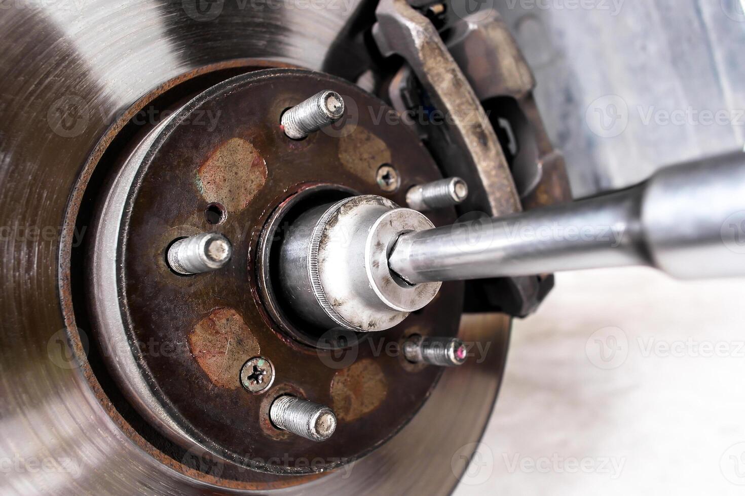 Close-up of removing a hub nut of front drive shaft or disc brake with mechanic tools to repair , Car repair concept photo