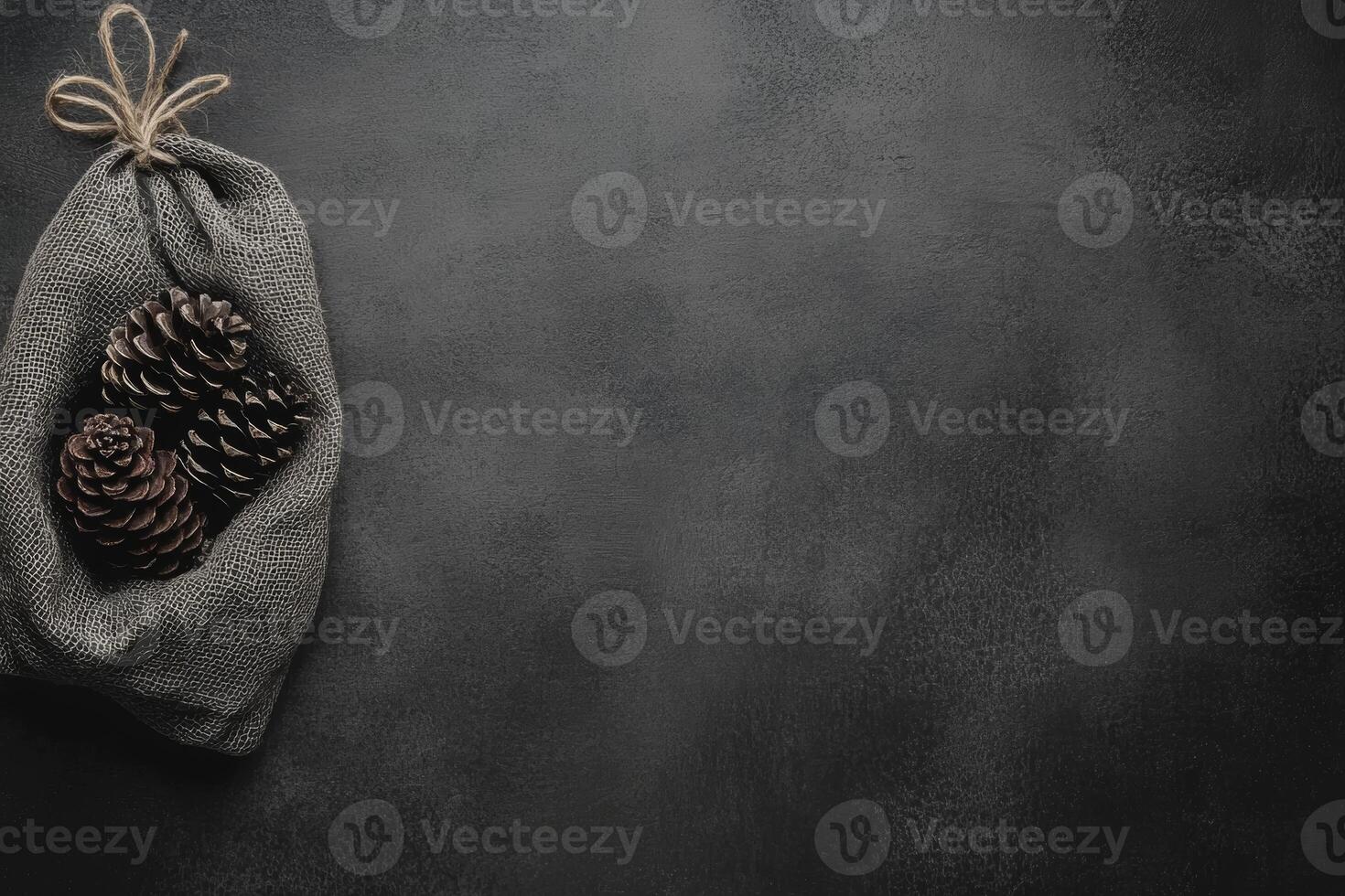 Pine Cones in a Burlap Sack on a Dark Gray Surface photo