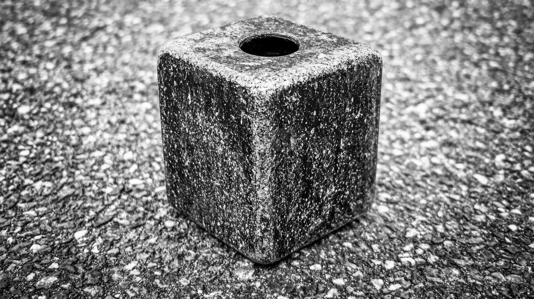 Monochrome Stone Cube with Central Hole on a Textured Surface photo