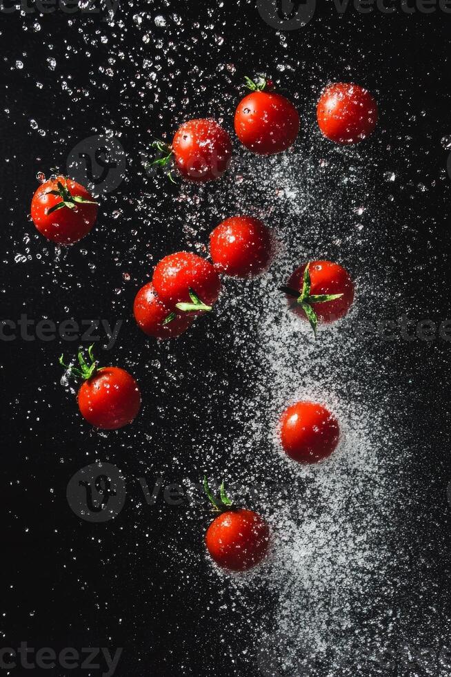 Scattered Cherry Tomatoes with Water Splashes on a Dark Surface photo