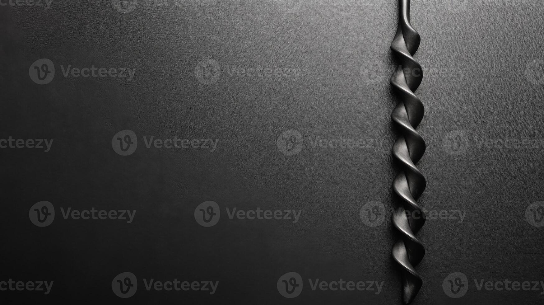 Twisted Black Drill Bit Against a Smooth Dark Textured Surface photo