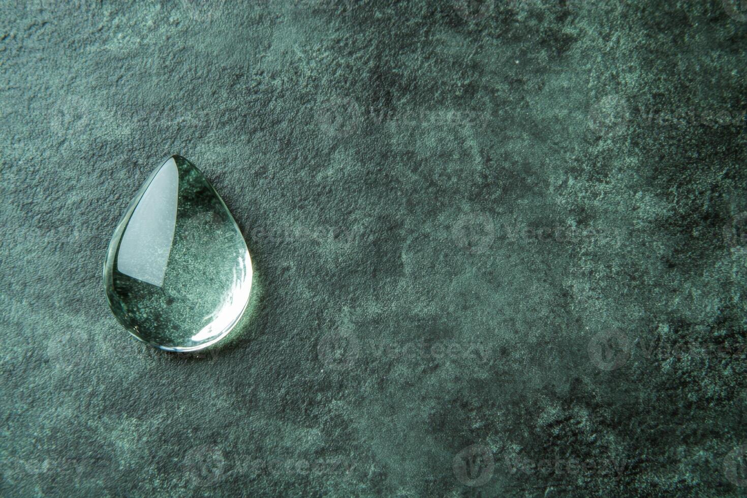 Clear Glass Droplet on a Textured Green Stone Surface photo