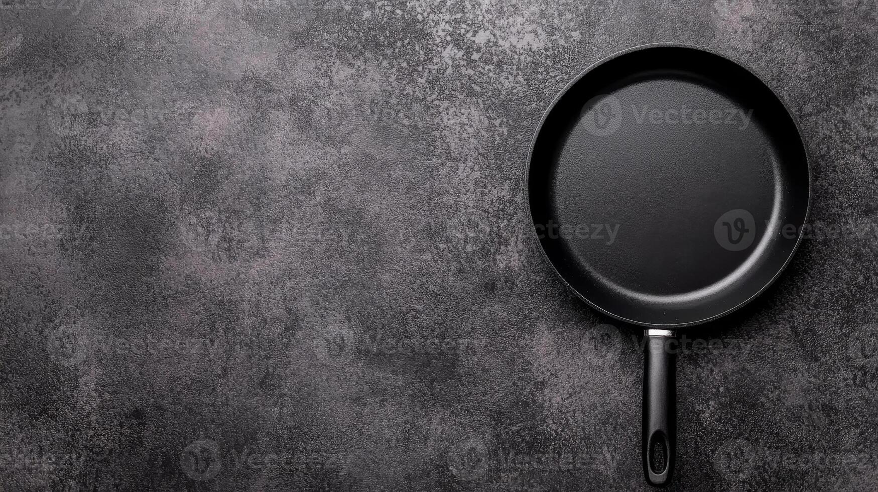 Black Frying Pan with Handle on a Textured Dark Gray Surface photo