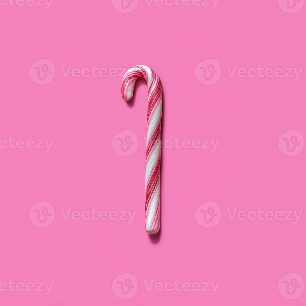 Classic Red and White Striped Candy Cane on Vibrant Pink Flat Lay photo