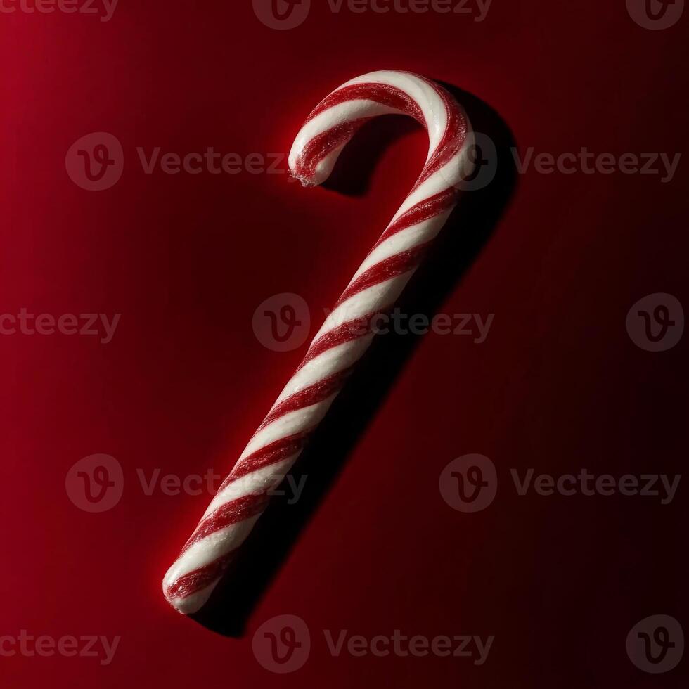 Close up of a red and white striped candy cane on a red surface photo