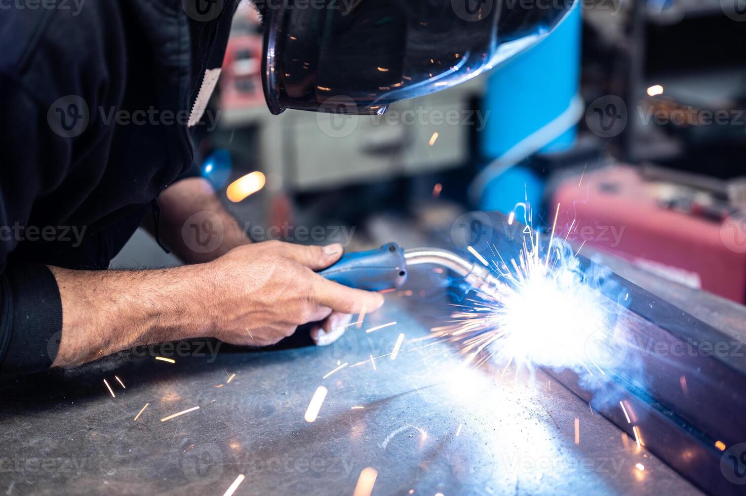 Carrying out a weld. The man in the welding mask positioned himself with the welding machine on the welding point, sparks,glow and smoke.Conceptual image of work,metalworking,craftsmanship. Copyspace. photo