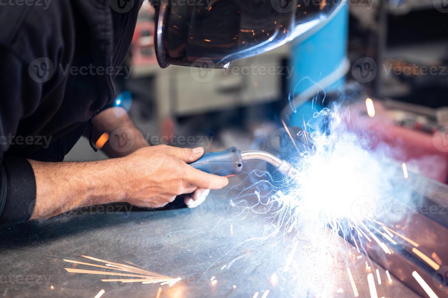 Carrying out a weld, the man in the welding mask positioned himself with the welding machine on the welding point, sparks,glow and smoke.Conceptual image of work,metalworking,craftsmanship. Copyspace. photo