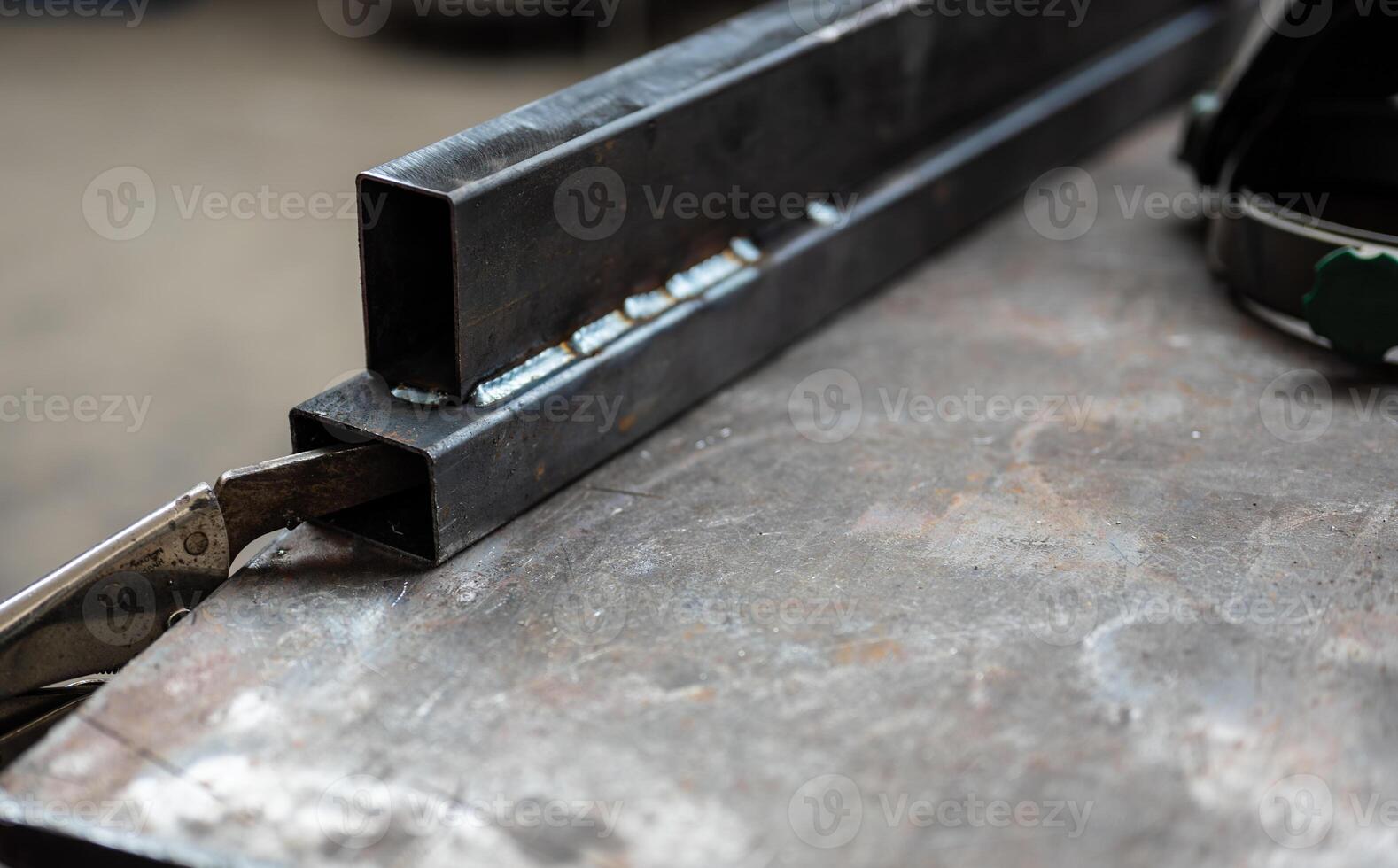Conceptual image at work, in a workshop selective focus on the welding point of two metal bars. Work concept, metal craft work, repair, creativity. photo
