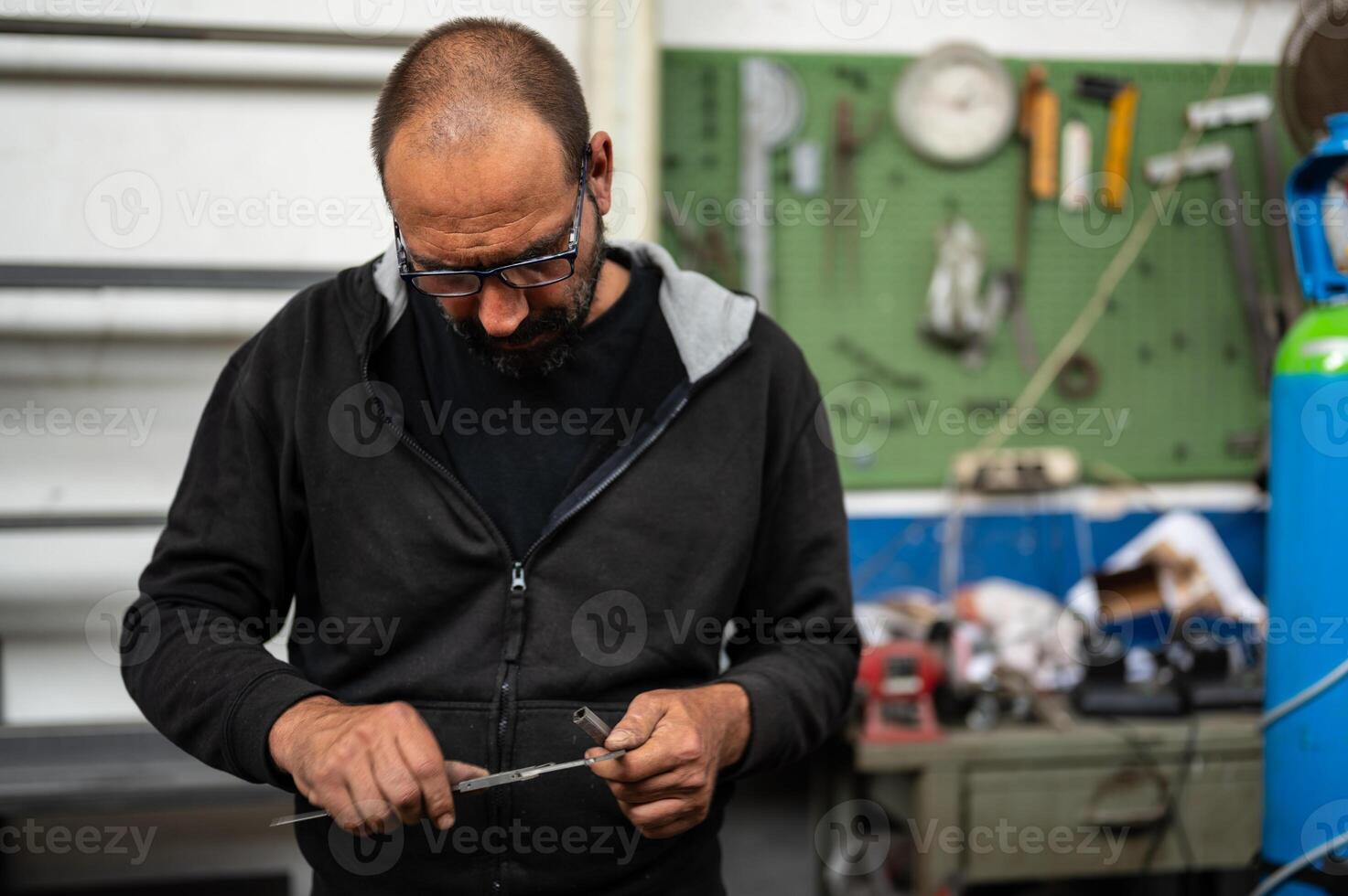 Conceptual photography about metal work, blacksmith is taking measurements of a metal bar with the use of caliper. Concept of reasoning at work, construction site in progress. photo