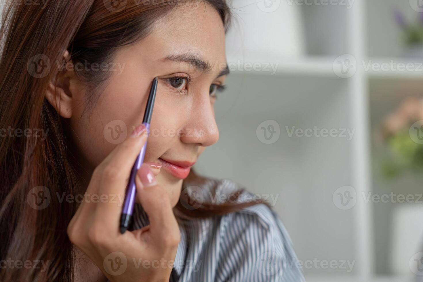 Makeup Application and Beauty Techniques. A woman applying eyeliner with precision. photo