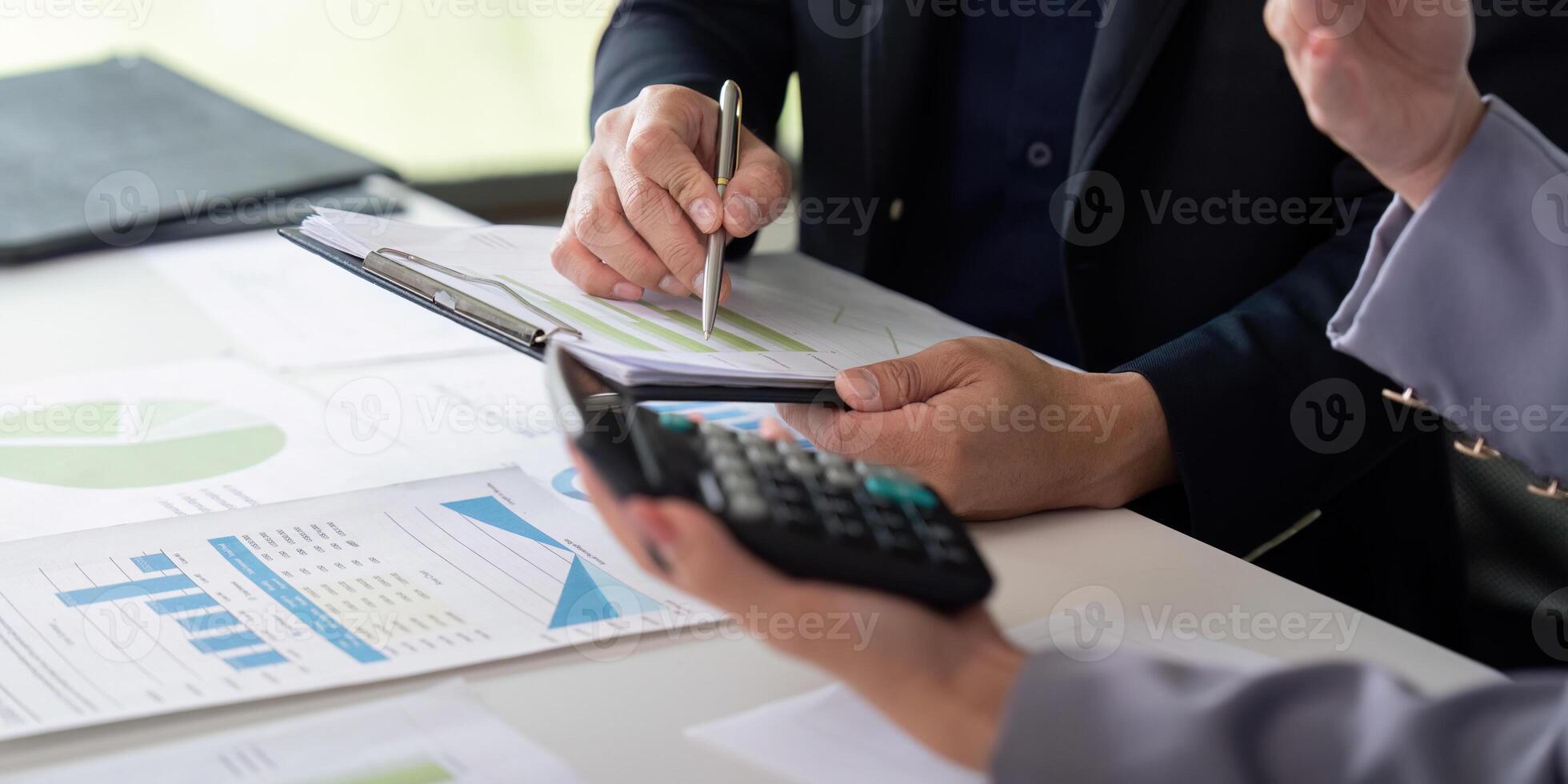 Collaboration and Financial Analysis. Colleagues discussing financial data with a calculator on the table. photo
