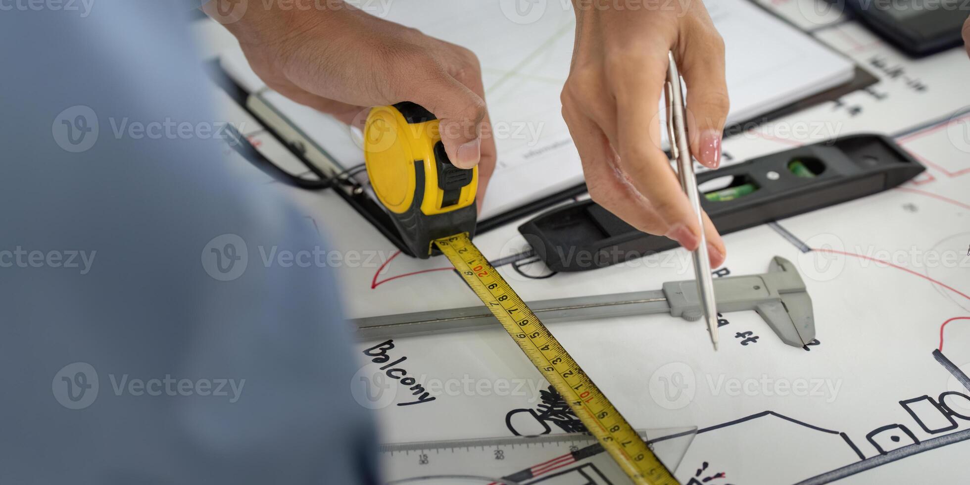Measuring and Planning. A colleague measuring dimensions of a building plan with precision tools. photo
