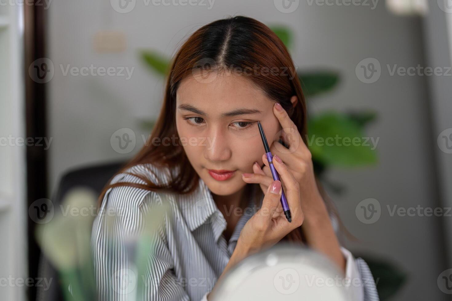 Eye Makeup and Precision. A woman skillfully applying eyeliner for a polished look. photo