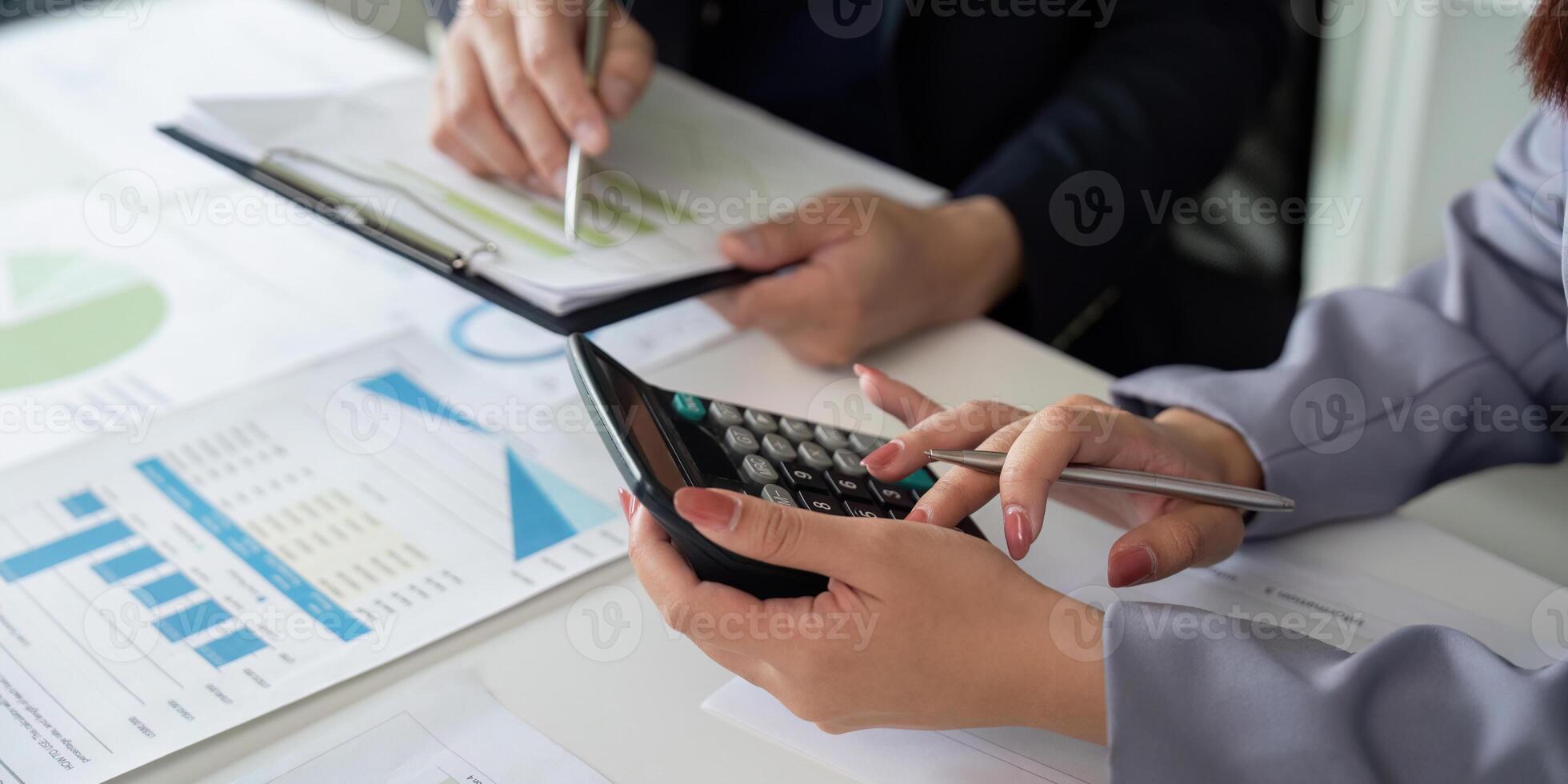 Calculation and Financial Analysis. A business professional using a calculator while discussing data. photo