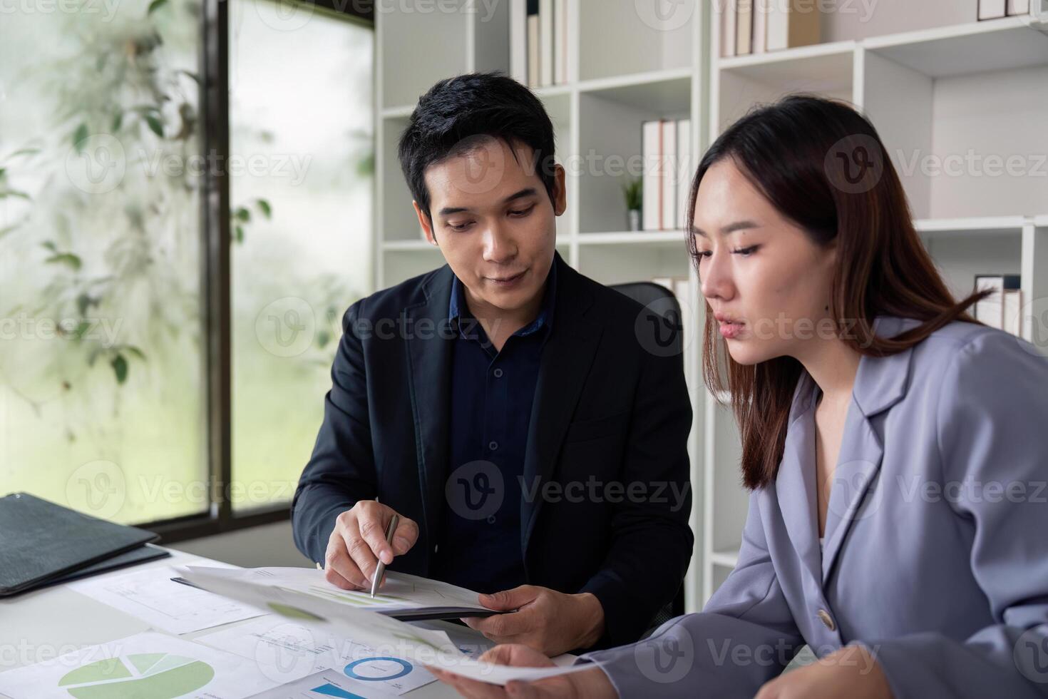 Financial Insights and Teamwork. Colleagues collaborating on financial reports in a bright office. photo