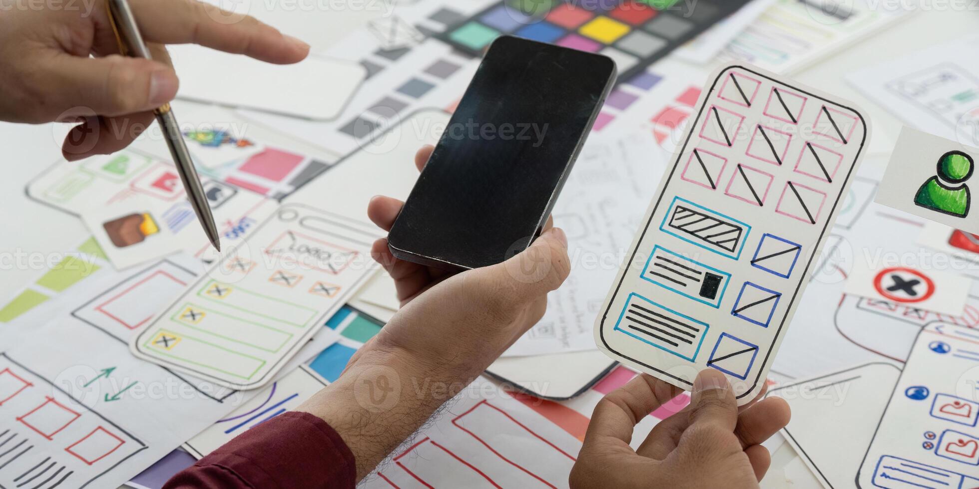 UX Design and Collaboration. Team members reviewing mobile app wireframes on a creative workspace. photo