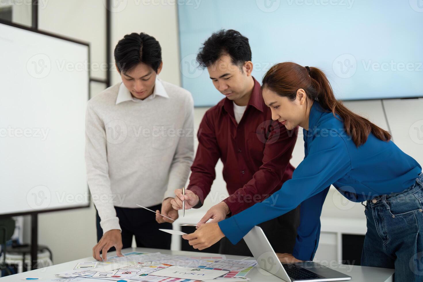 Teamwork in UX UI Development. A focused discussion among UX UI designers as they work collaboratively on design layouts. photo