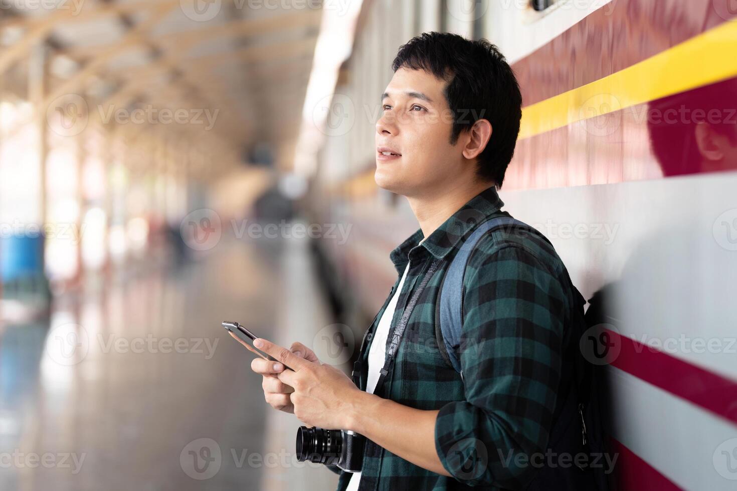 Contemplation and Waiting. A traveler standing at a train station wall, awaiting the arrival of his train. photo