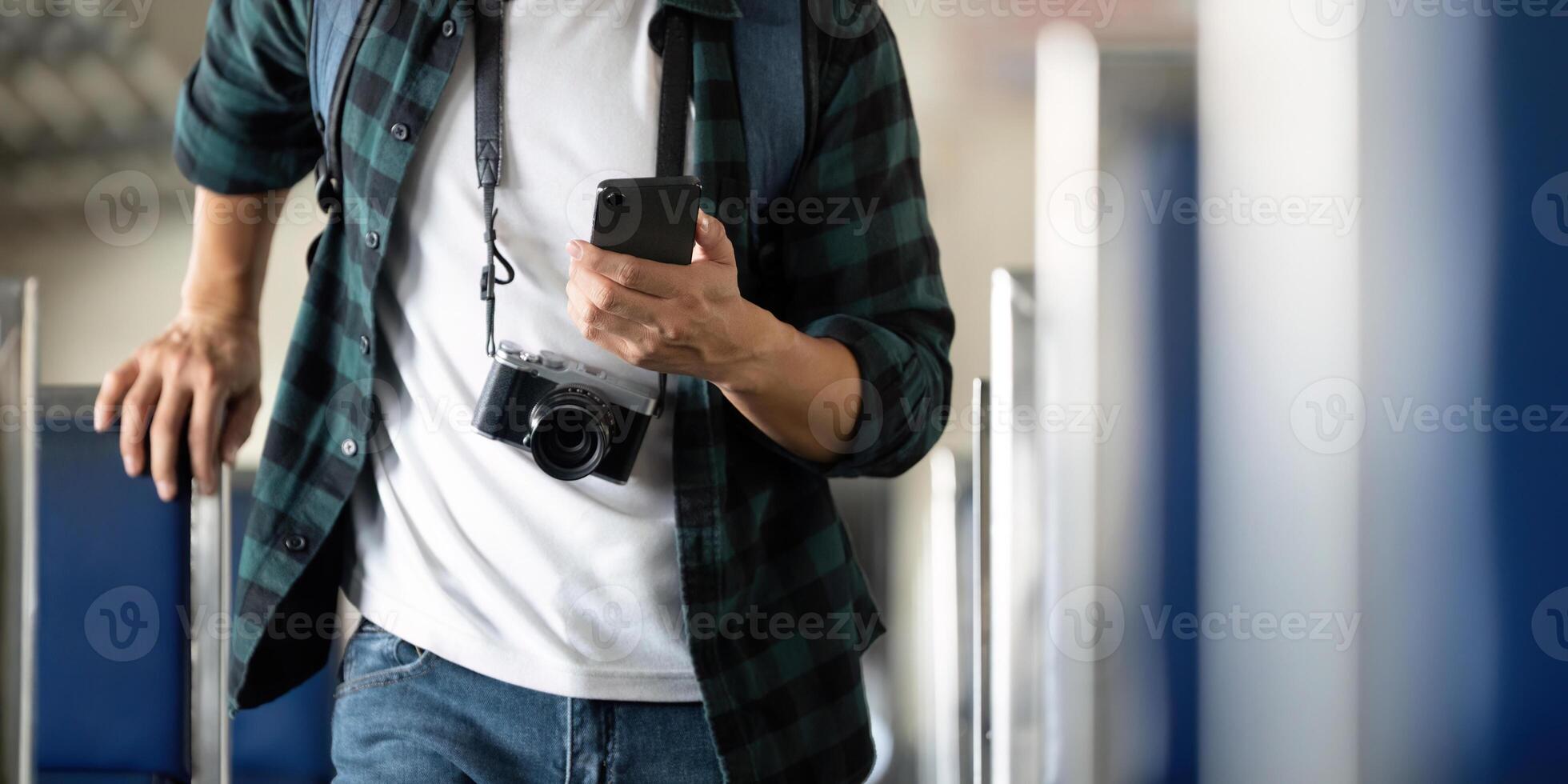 Travel and Photography. A young man with a camera checks his phone while exploring a train. photo