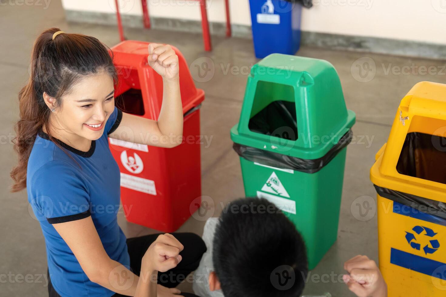 Teamwork and Sustainability Awareness. A young woman engages a child in recycling games near bins. photo
