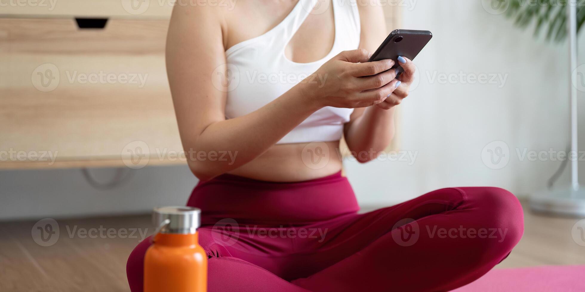 Hydration and Self-Care. A woman checking her phone after a yoga session, highlighting the importance of hydration and wellness. photo