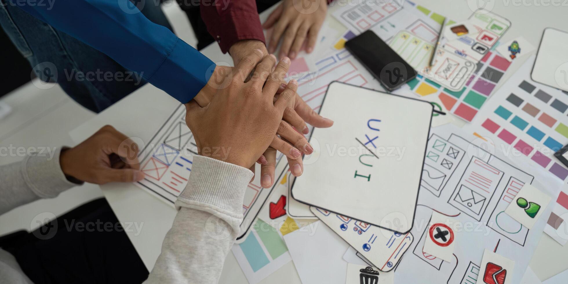 Collaboration and UX UI Design. Team members unite hands over design concepts, emphasizing teamwork in the UX UI design process. photo