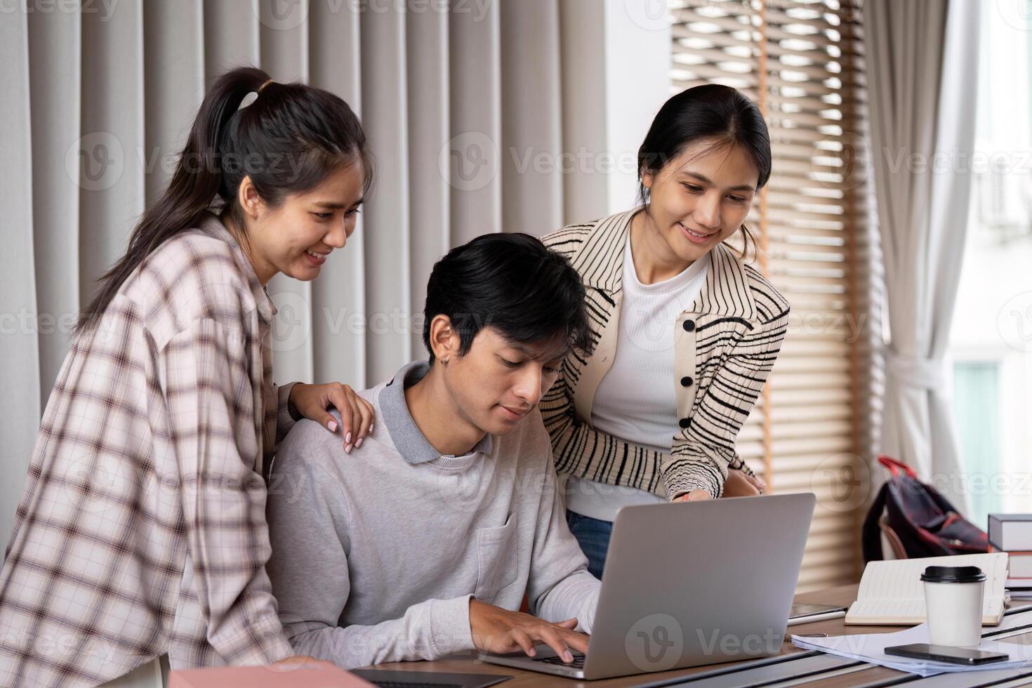 Studying Together and Exploring Ideas. Three friends discussing and sharing knowledge while working on a laptop. photo