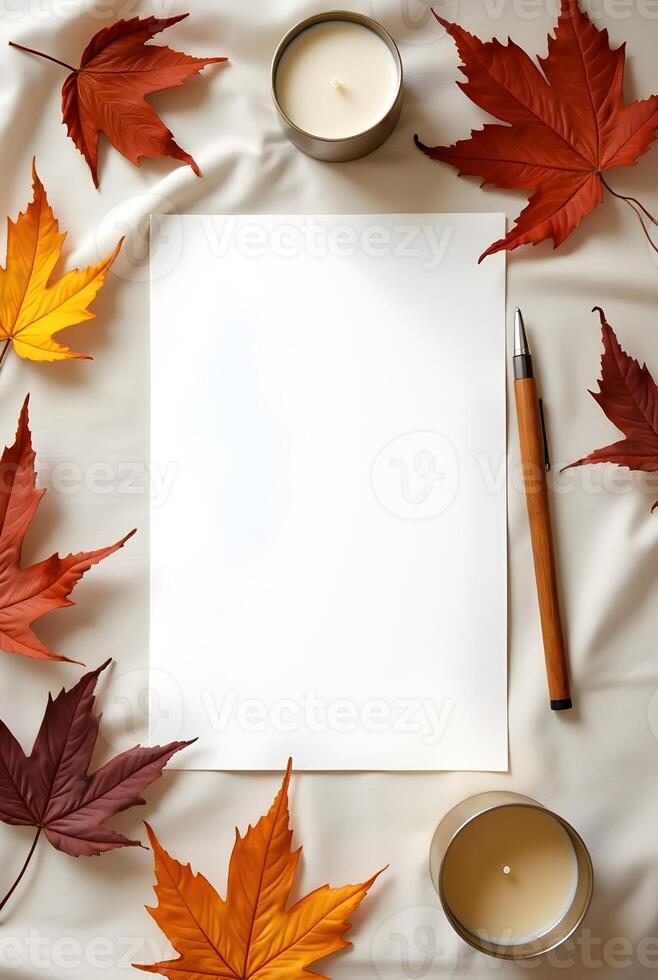 Blank paper with leaves, pen, and a candle on a soft fabric background photo