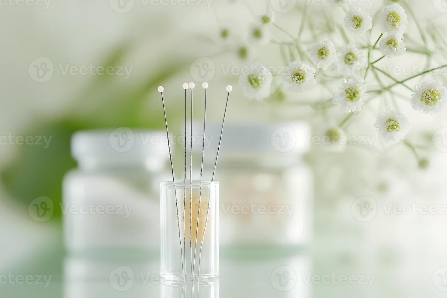 Acupuncture needles in a glass jar with flowers photo