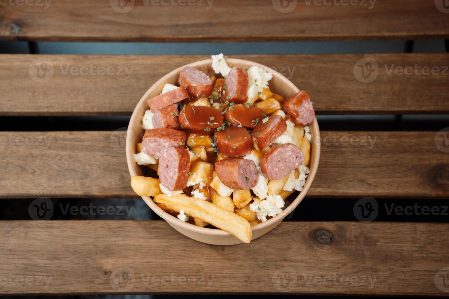 Poutine fries with chees and sausage in paper takeout container. Delicious freshly prepared meal, perfect for menus, restaurants, or food delivery concepts. photo