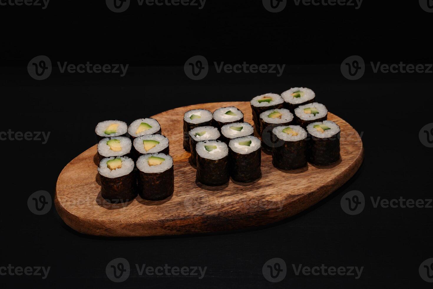 Creative minimalist display of assorted Maki sushi rolls on a wooden platter against a dark backdrop, emphasizing vibrant colors and exquisite Japanese culinary art with a modern aesthetic. photo