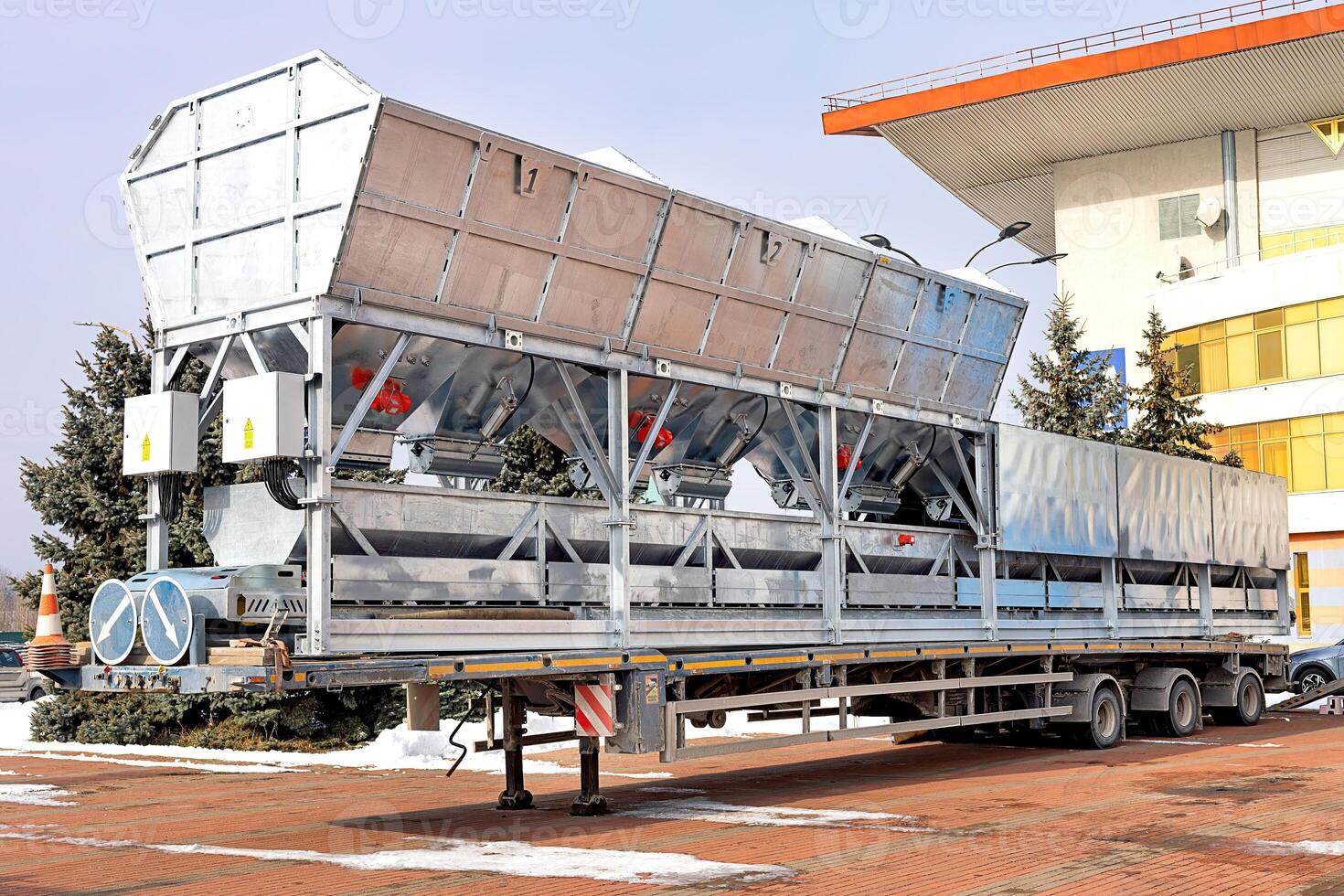 Large transport trailer with hoppers and red vibrators and shakers for ready-mix concrete mixing plants. photo