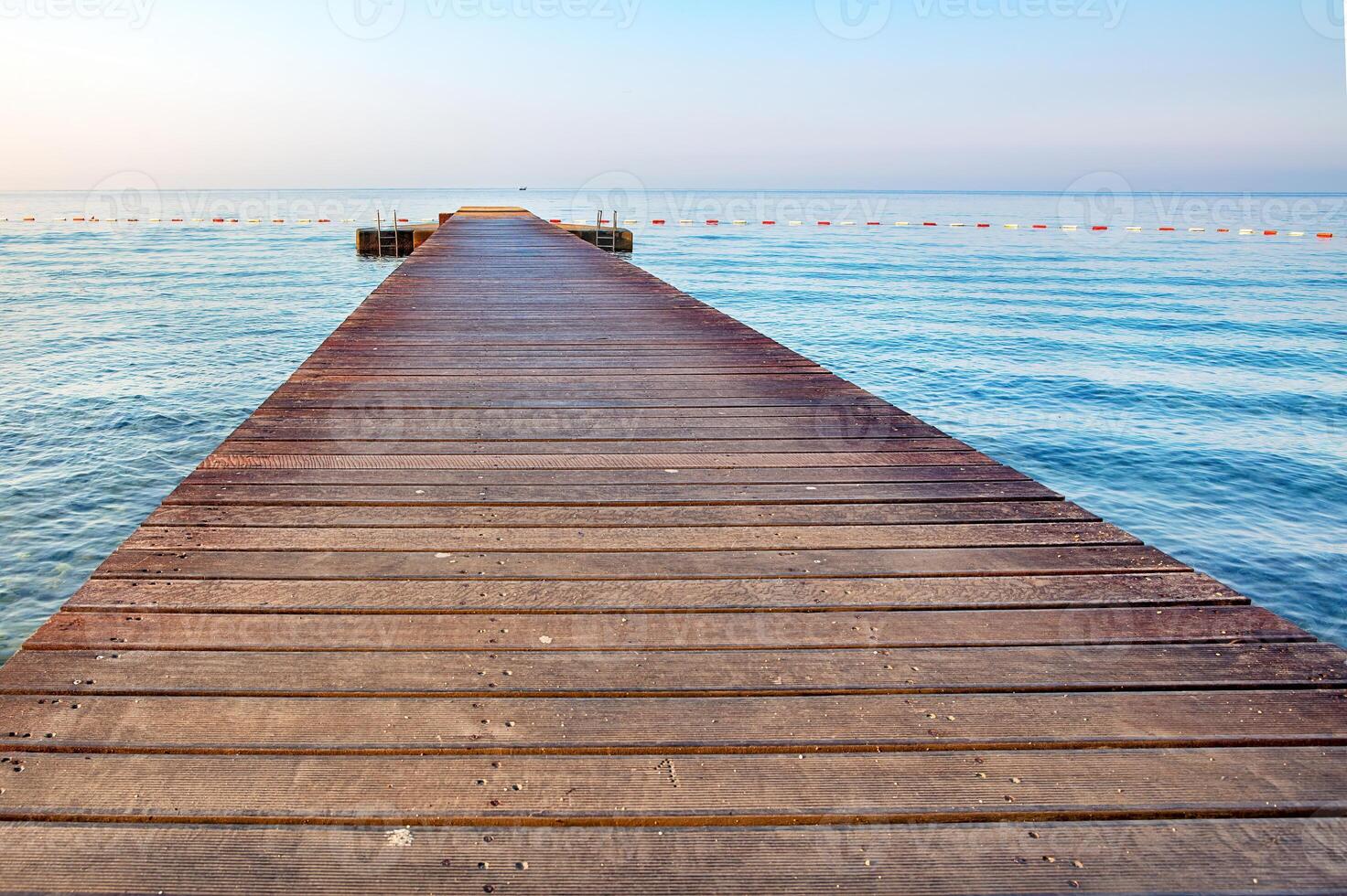 Serene wooden pier stretches into calm waters during early morning light photo
