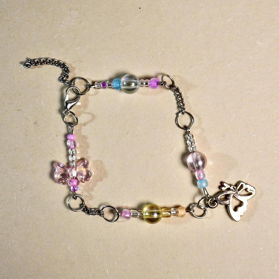 Cute colorful decorative handmade diy bracelet beads accesories with metal rings and chains isolated on brown paper surface background. photo