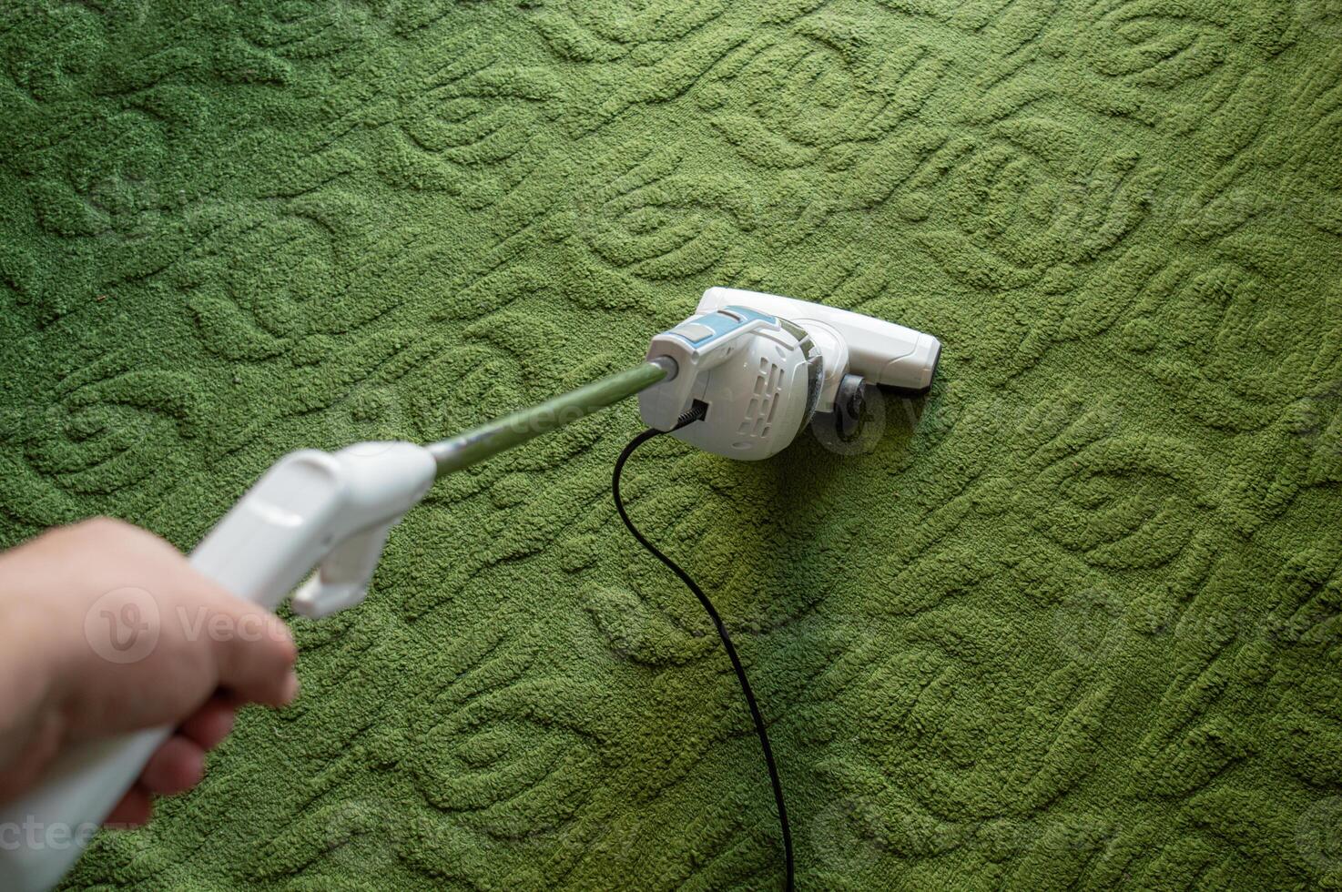vacuuming the floor in the first person. The white hoop is cleaning the green carpet. High quality photo