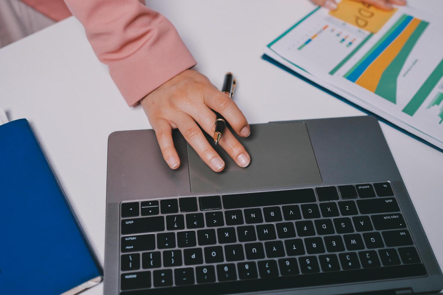 A person is typing on a laptop with a pen and notebook photo