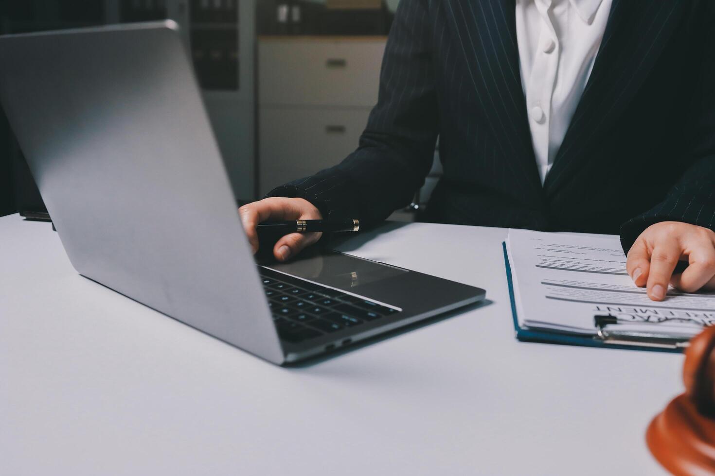 A man in a suit is using a laptop on a desk photo