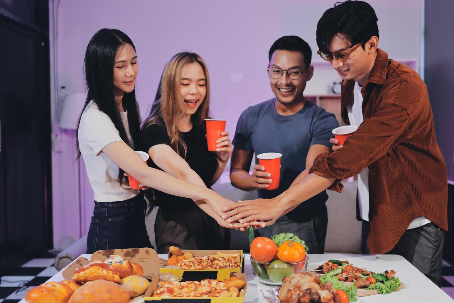 A group of people holding hands around a table with food photo