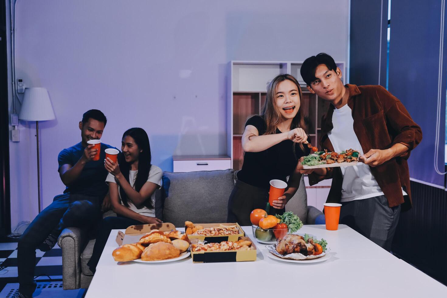A group of people eating food in a living room photo