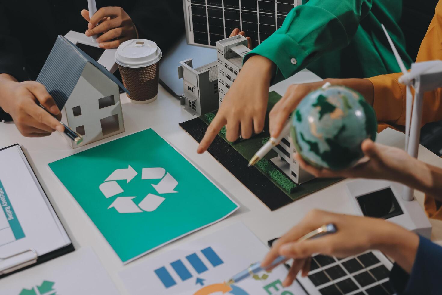 A group of people are working on a paper with recycling symbols photo