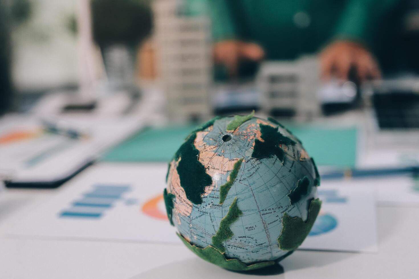 A small globe on a table with a business person in the background photo