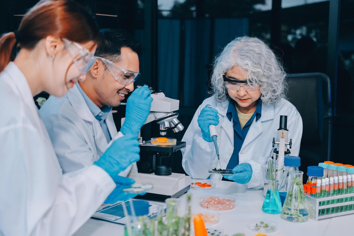 Three people in lab coats and gloves looking at something photo
