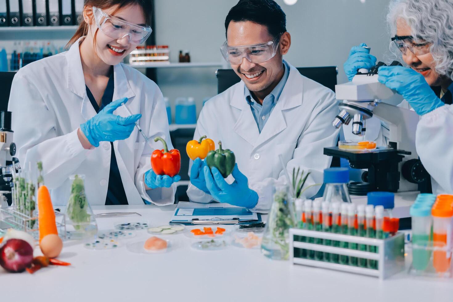 Three people in lab coats and gloves looking at vegetables photo