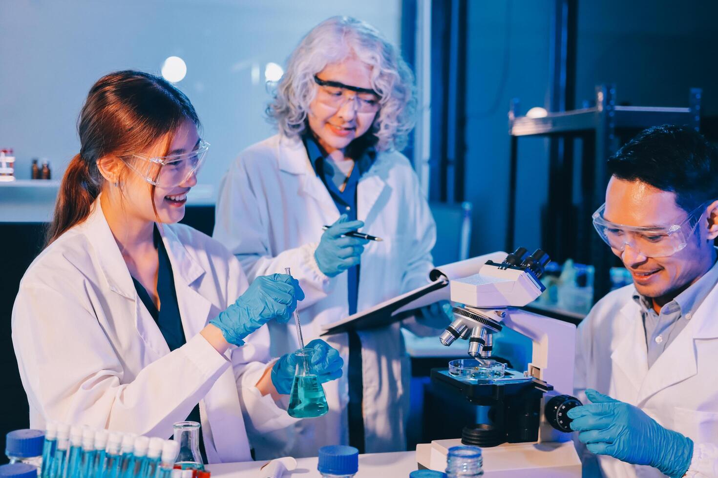 Three people in lab coats looking at something photo