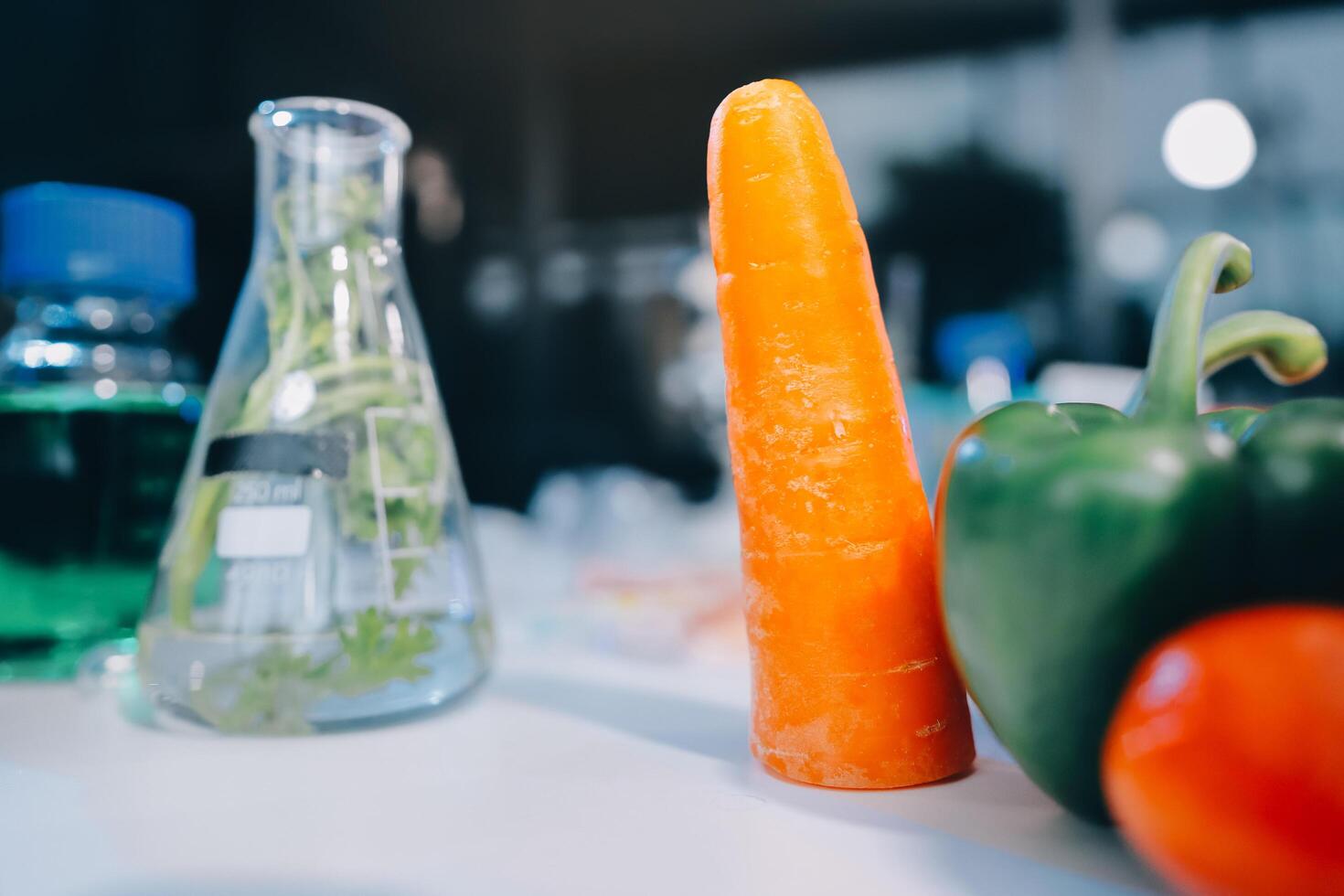 A carrot, pepper and a glass bottle on a table photo
