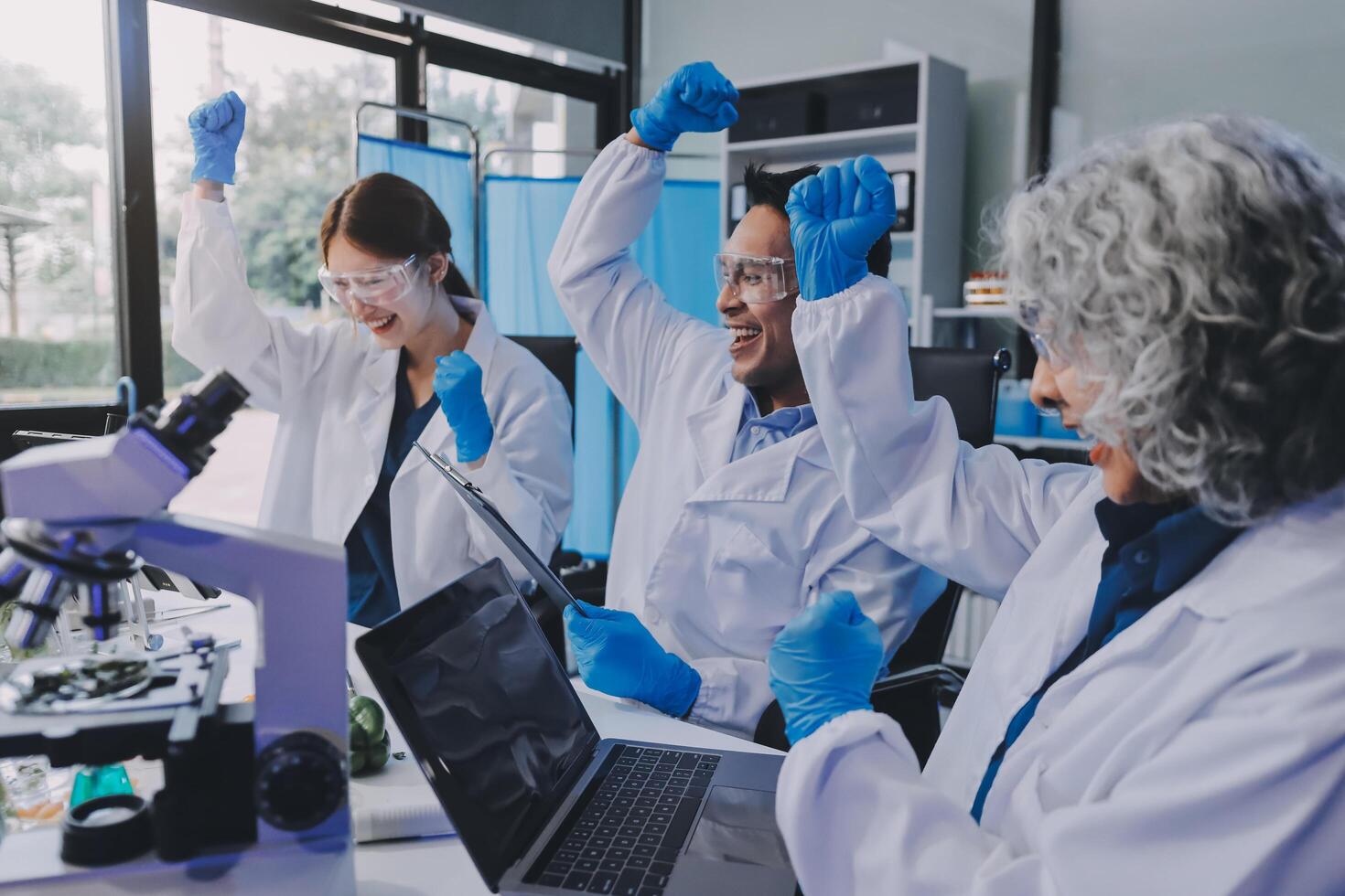 Three people in lab coats and gloves are working on a laptop photo