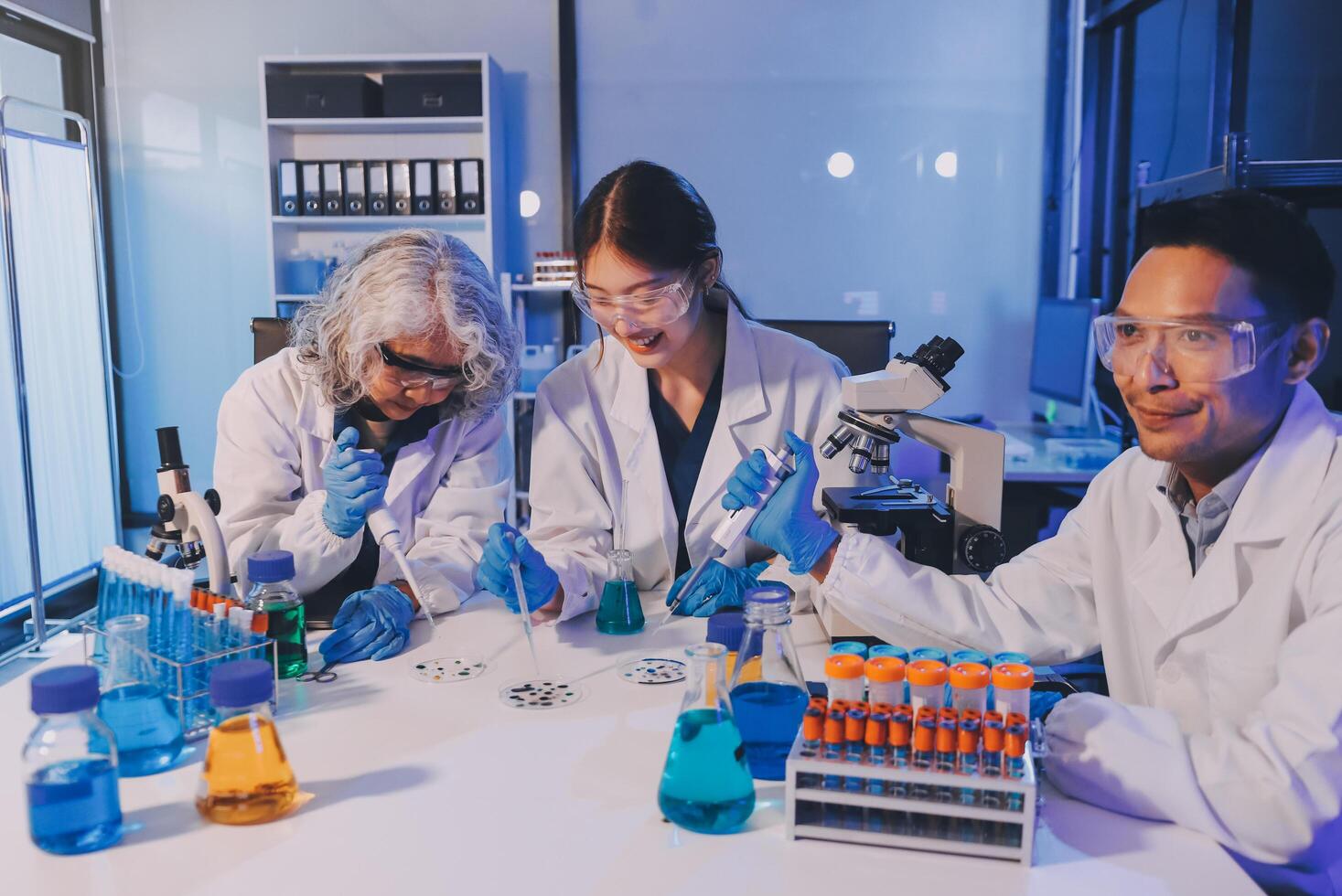 Three people in lab coats working together photo