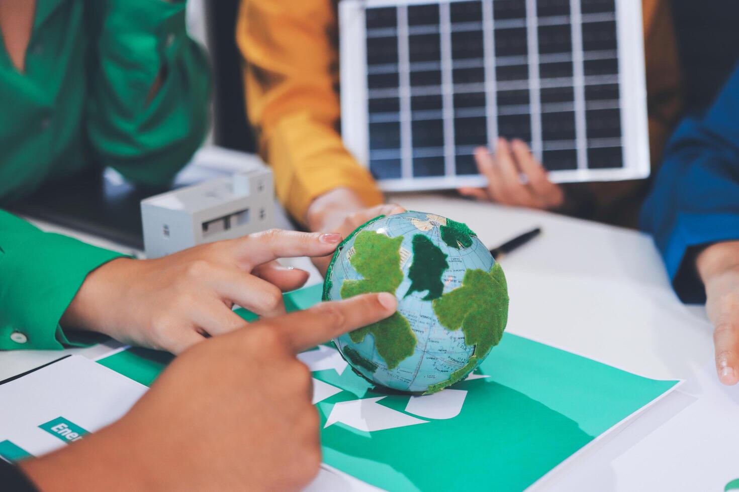 People working on a green earth globe with solar panels photo